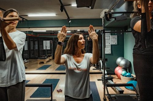 Pilates instructor guiding two women during a workout in a modern gym environment.